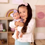 Lalka niemowlę ze smoczkiem, w ubranku w kwiatuszki i opasce, fioletowa / LullaBaby