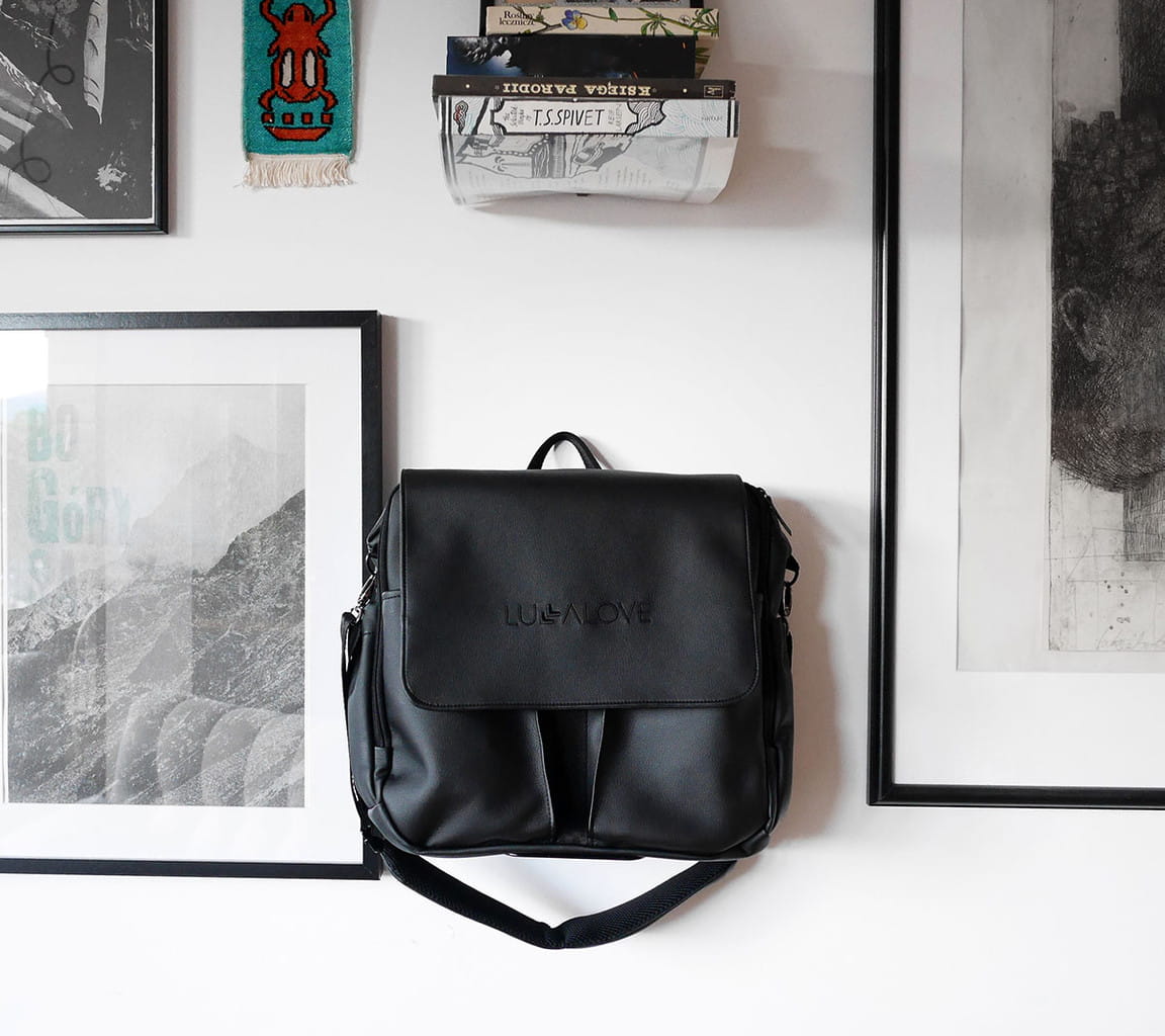 Czarny plecak/torba z kieszeniami zaczepiony na ścianie 