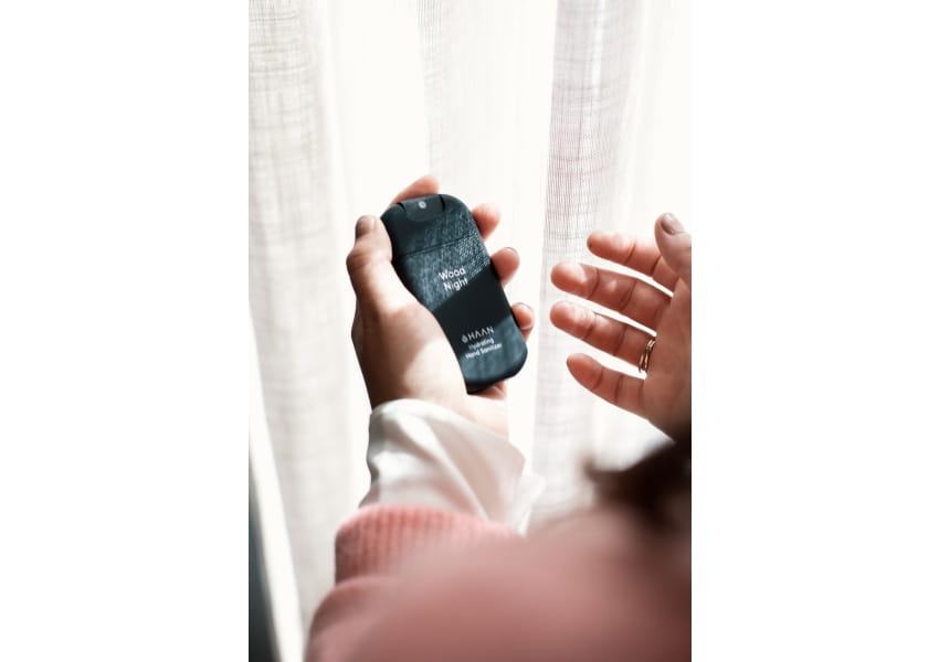 Męskie dłonie i czarne opakowanie sprayu dezynfekującego