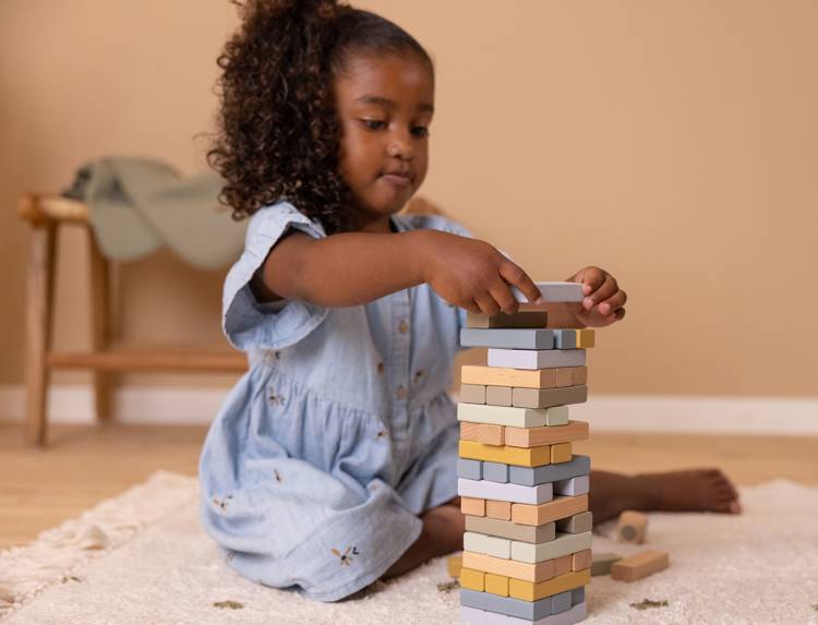 Dziewczynka bawi się drewnianą grą jenga