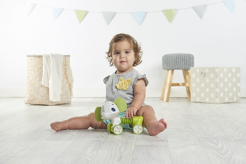 Dziewczynka siedzi na podłodze z zabawką słonikiem