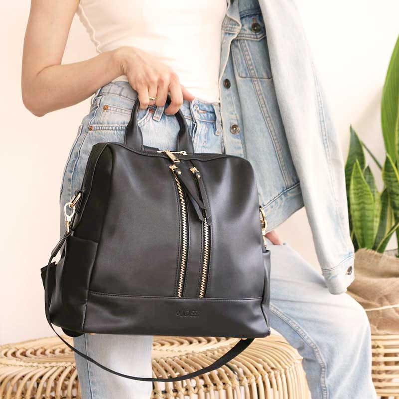 Kobieta trzyma w dłoni torbę/ plecak w kolorze czarnym