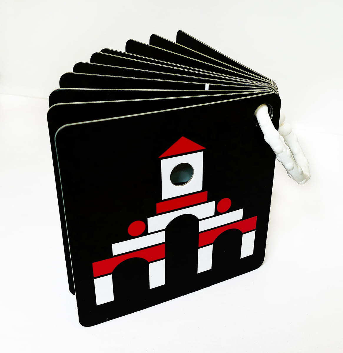 Zawieszka z ilustracją na czarnym tle - biały domek z wieżyczkami i czerwoną dachówką i innymi elementami elewacji