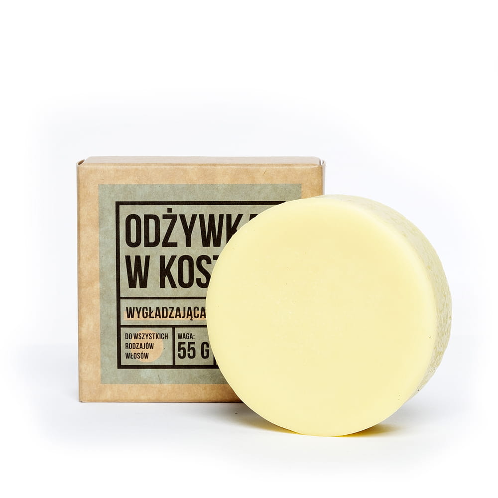 Odżywka w kostce - w tle opakowanie papierowe z napisami a na pierwszym planie jasny krążek odżywki