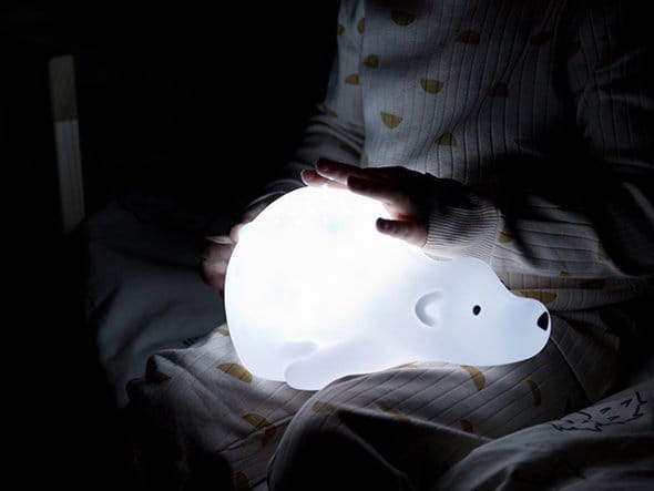 Dziecko trzyma na kolanach projektor-lampkę Misia, który się świeci