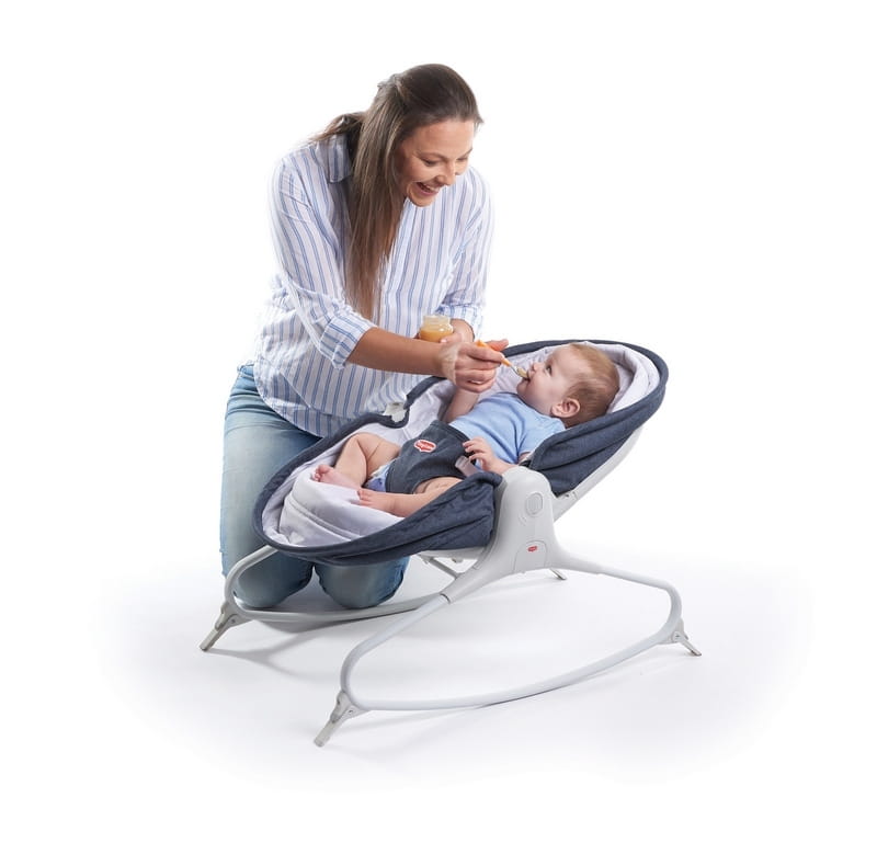 Dziecko leży w leżaczku a mama karmi je łyżeczką 